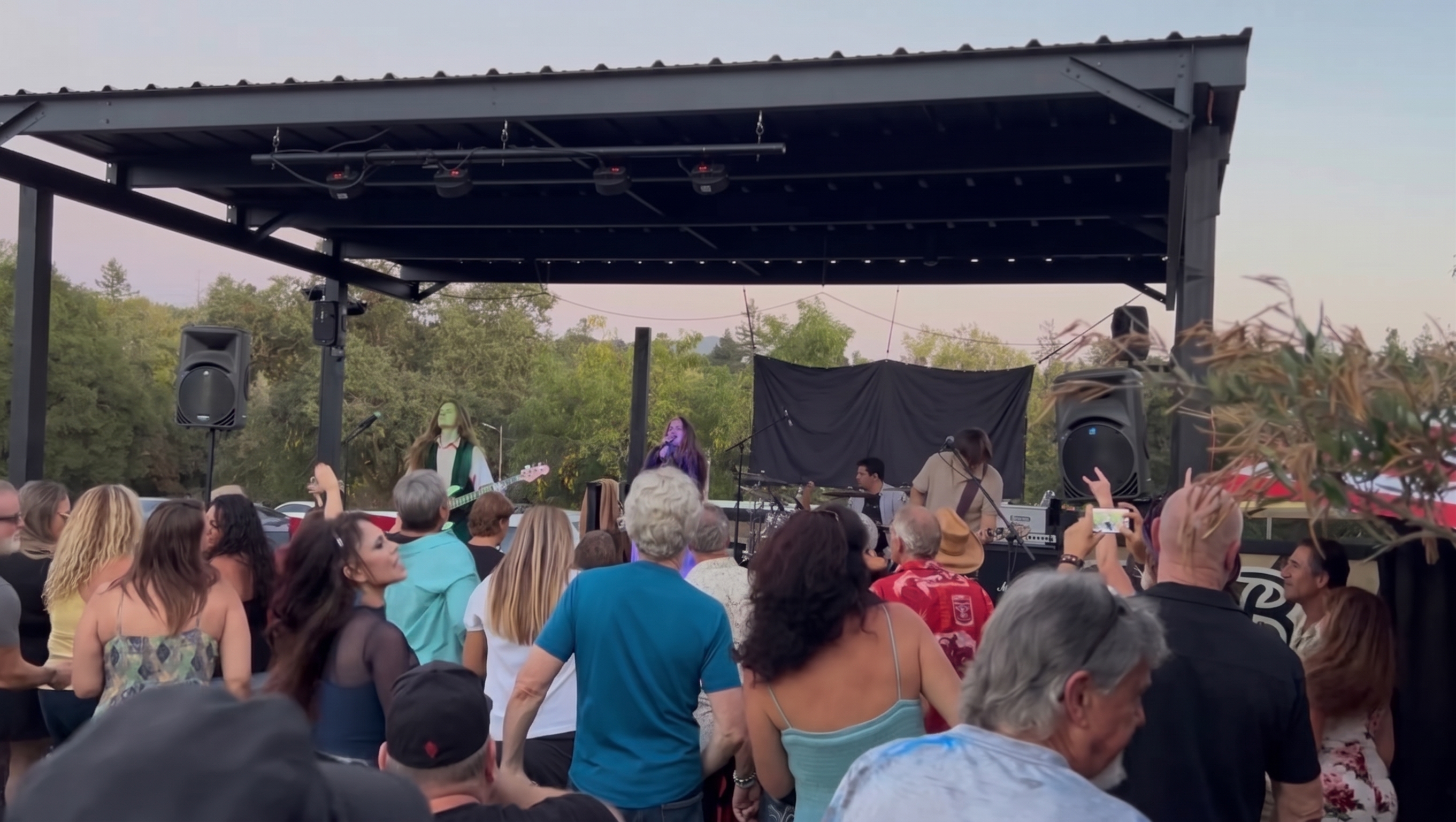Live band performing on the covered backyard stage pavilion at dusk