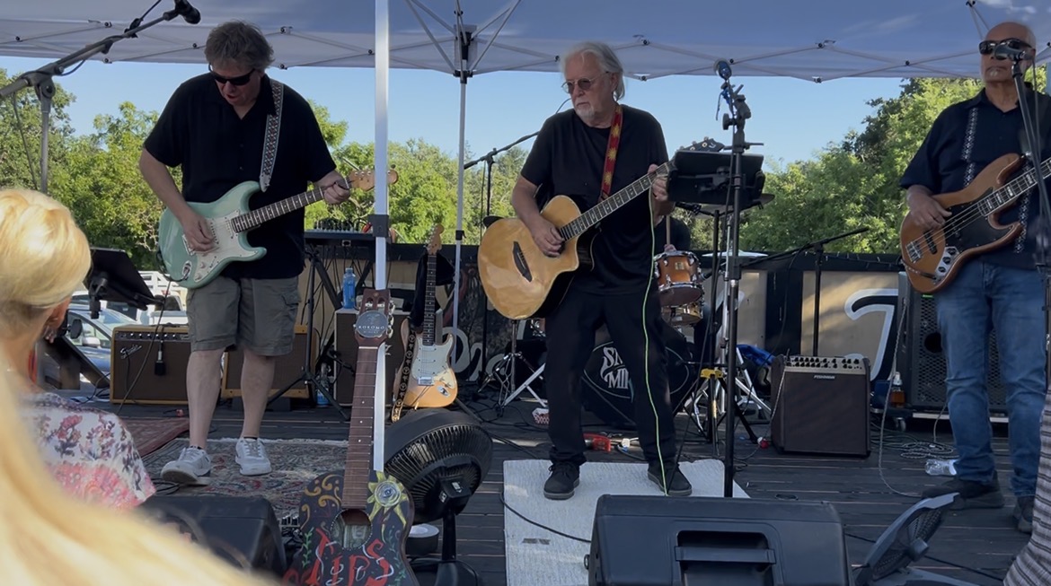 Acoustic rock trio performing outdoor afternoon live music set